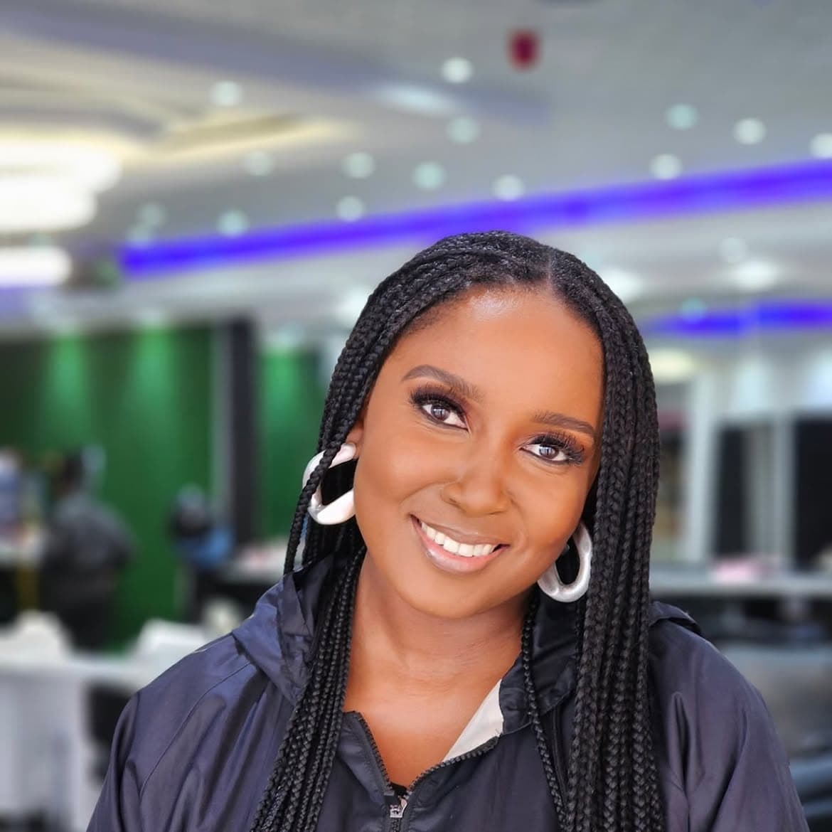 Radiant portrait featuring micro-box braids, sculpted brows, and soft rose blush
