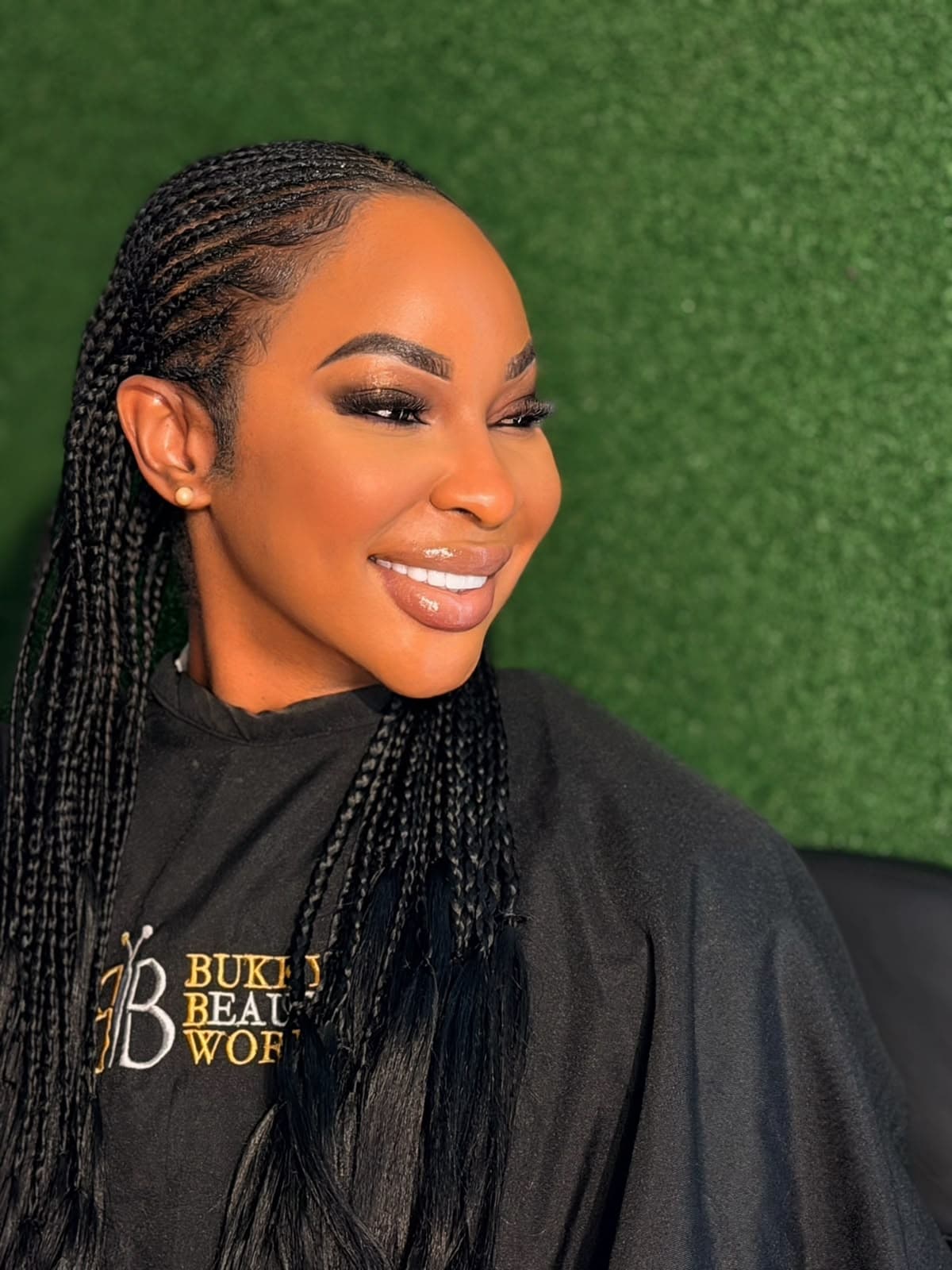 Flawless bronze contour, radiant smile, and micro-braids in Bukky Beauty World studio