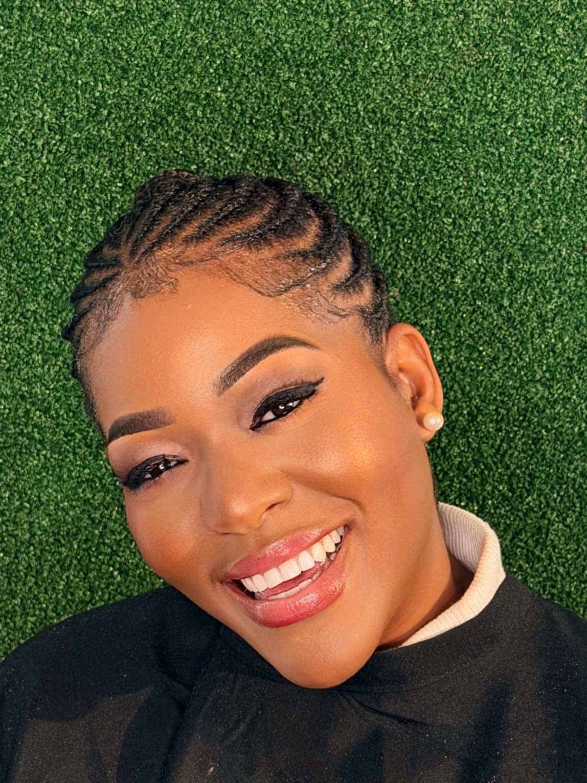Luminous warm skin and winged liner with precision scalp cornrows and bright smile